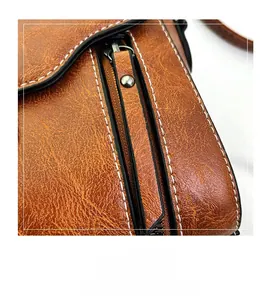 Close-up of caramel brown retro leather bag featuring smooth zipper and white stitching