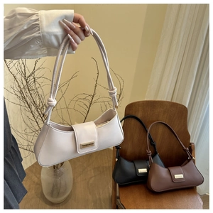 Detail of elegant baguette bag with knot strap design and gold metal buckle closure