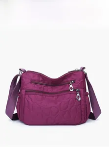 Front view of purple nylon crossbody bag with heart quilting and multi-zipper pockets