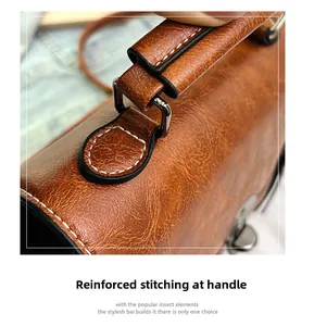 Detail of reinforced stitching and silver hardware on a brown textured leather handbag