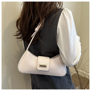 Detail of cream baguette bag featuring a gold metal buckle and unique knotted shoulder strap