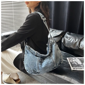 Detail view of large blue denim tote bag with adjustable strap worn on shoulder