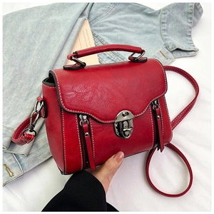 Detail of red vintage crossbody bag with white contrast stitching and silver hardware