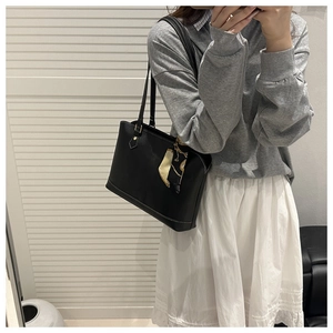 Detail of black leather tote bag with white contrast stitching and decorative silk scarf