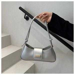 Detail of silver metallic baguette bag showing side knots and golden metal plate