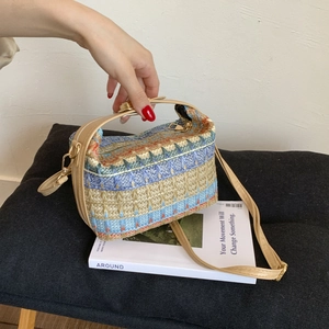 Dettaglio della borsa etnica intrecciata con motivi geometrici e finiture in metallo oro