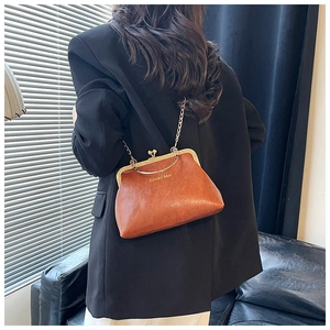 Dettaglio della borsa a scatto marrone vintage con catena dorata indossata da una modella