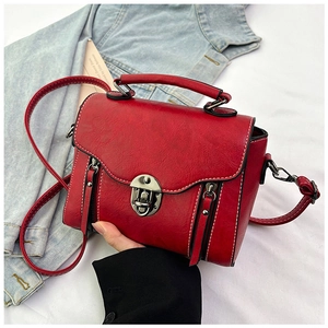 Detailed view of red retro PU leather crossbody bag with metal twist lock and stitching