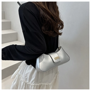 Detail of silver metallic baguette bag with gold buckle on a minimalist background