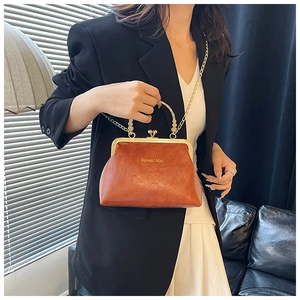 Dettaglio della borsa vintage marrone con catena e chiusura a sfera su una modella