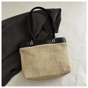 Detail of hand-woven straw texture and black leather stitching on a chic summer tote bag