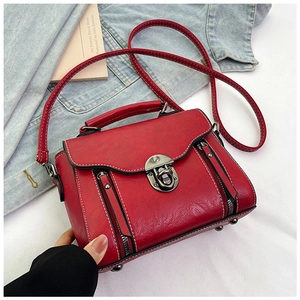 Detail showing vintage red PU leather crossbody bag with metal lock and zipper texture