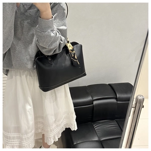 Detail of black tote bag showing white contrast stitching and elegant chain pattern scarf