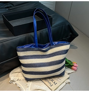 Detail of blue and white striped woven tote bag featuring glossy handles and interior lining