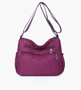 Detail of purple nylon crossbody bag with heart quilting and multiple zipper pockets
