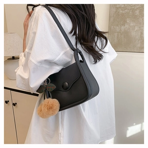 Detail of black crossbody bag featuring scalloped flap design and leaf plush charm