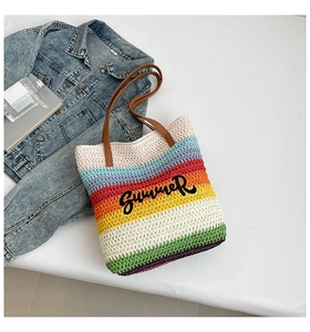 Detail shot of a rainbow striped straw tote bag with SUMMER embroidery and leather handles