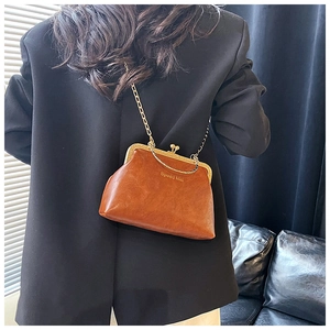 Dettaglio di una borsa a scatto vintage in pelle marrone con catena dorata