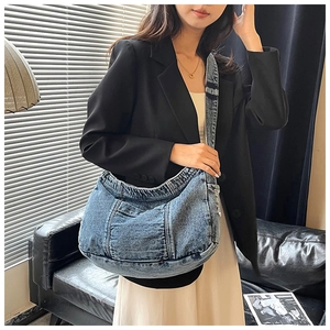 Blue washed denim crescent bag styled with a black blazer in a cozy home setting