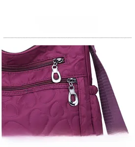 Detail of silver dual ring zippers and heart quilted pattern on purple nylon bag