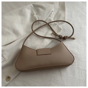 Close-up of mocha brown leather bag with elegant knot strap and magnetic flap detail