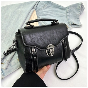 Detailed close-up of retro black PU leather square bag with white contrast stitching