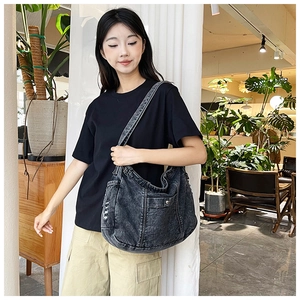 Detail of vintage washed black denim shoulder bag with metal button and wide strap