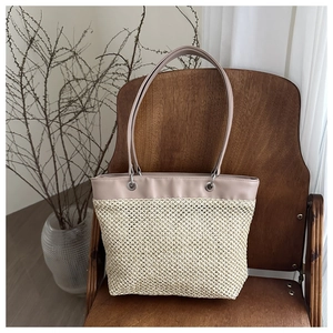 Detail of woven straw tote bag with lavender leather straps on a wooden chair