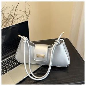 Close-up of silver faux leather baguette bag with gold metal buckle on a desk