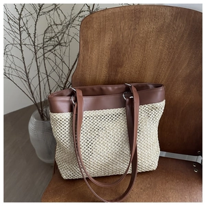 Detailed close-up of straw woven tote bag with brown leather trim on vintage wooden chair