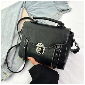 Detail of black crossbody bag with white stitching and silver metal buckle closure