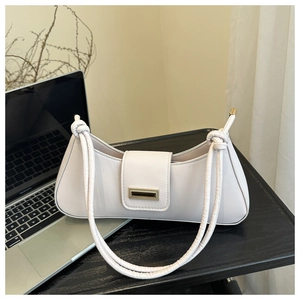 Detail of ivory faux leather baguette bag featuring gold buckle and knotted shoulder strap