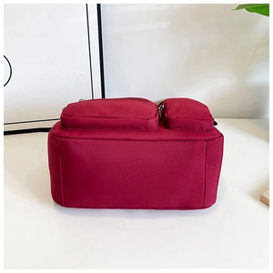 Détail macro du sac de voyage en nylon bordeaux avec deux poches frontales zippées