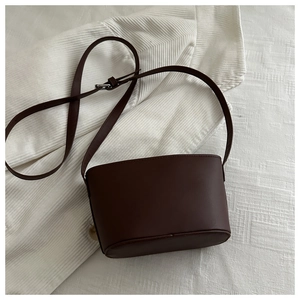 Detail of a dark brown bucket bag with smooth matte finish and adjustable silver buckle