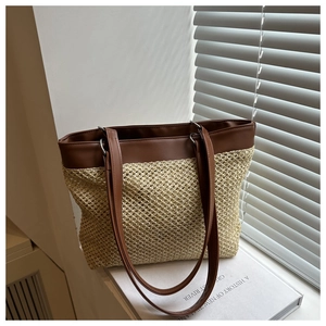 Detailed view of beige straw woven texture and brown leather straps on summer tote bag