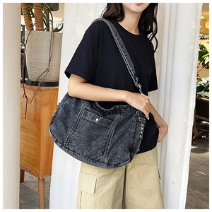 Close-up of vintage washed denim crossbody bag featuring metal snap pocket and broad strap