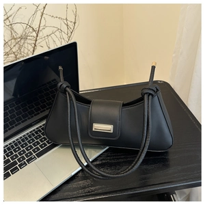 Detail of black faux leather baguette bag featuring a silver buckle and knotted strap