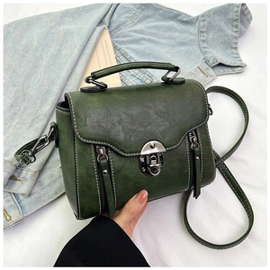 Detail of dark green vintage handbag with textured faux leather and metal lock