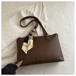 Detail of dark brown leather tote with decorative chain print silk scarf on handle