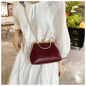 Dettaglio borsa vintage bordeaux con tracolla a catena dorata e chiusura a scatto