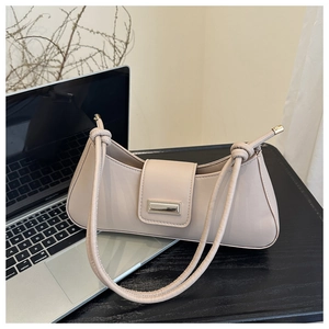 Detail of the nude leather shoulder bag featuring a knotted strap and magnetic metal clasp