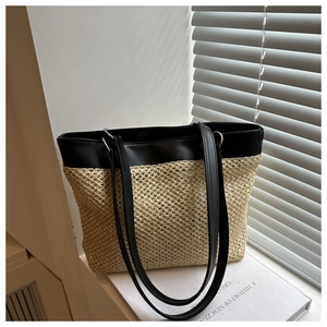 Detail of beige straw weave texture and black faux leather handle on summer tote bag
