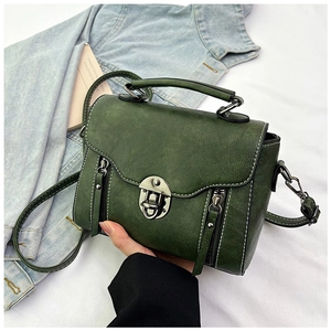 Detail of dark green vintage crossbody bag with white stitching and metal clasp