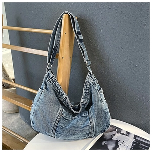 Detailed shot of retro washed blue denim hobo bag featuring side pockets and wide strap