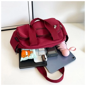 Détail du sac en toile bordeaux montrant sa grande capacité avec des objets du quotidien