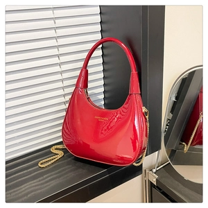 Detail of red patent leather crescent bag with gold chain and brand logo engraving