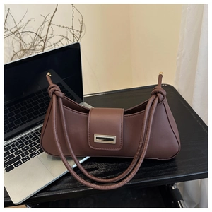 Close-up of brown curved shoulder bag with gold metal buckle and knotted strap detail
