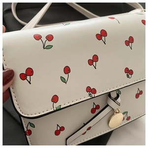 Détails du mini sac bandoulière à motif cerise avec pendentif doré et nœud élégant