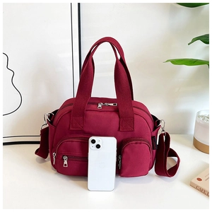 Détail du sac en nylon bordeaux avec poches zippées montrant la taille avec un téléphone