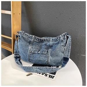 Detail of blue denim hobo bag with metal buckle pocket on a magazine background
